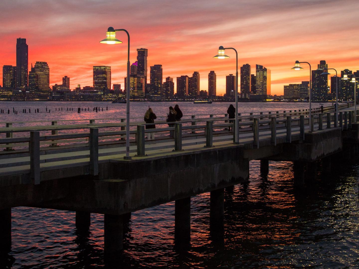 Pier 34 at dusk along an orange and pink Hudson River sunset